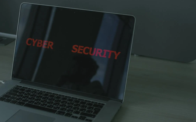 The image shows a laptop screen displaying the words "Cyber Security", suggesting a focus on computer security and protection against digital threats.