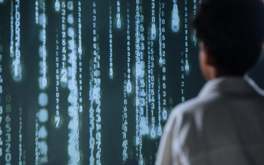 The image depicts a person silhouetted against a backdrop of cascading lines of digital code, suggesting a focus on technology, data, or computer-related tasks.