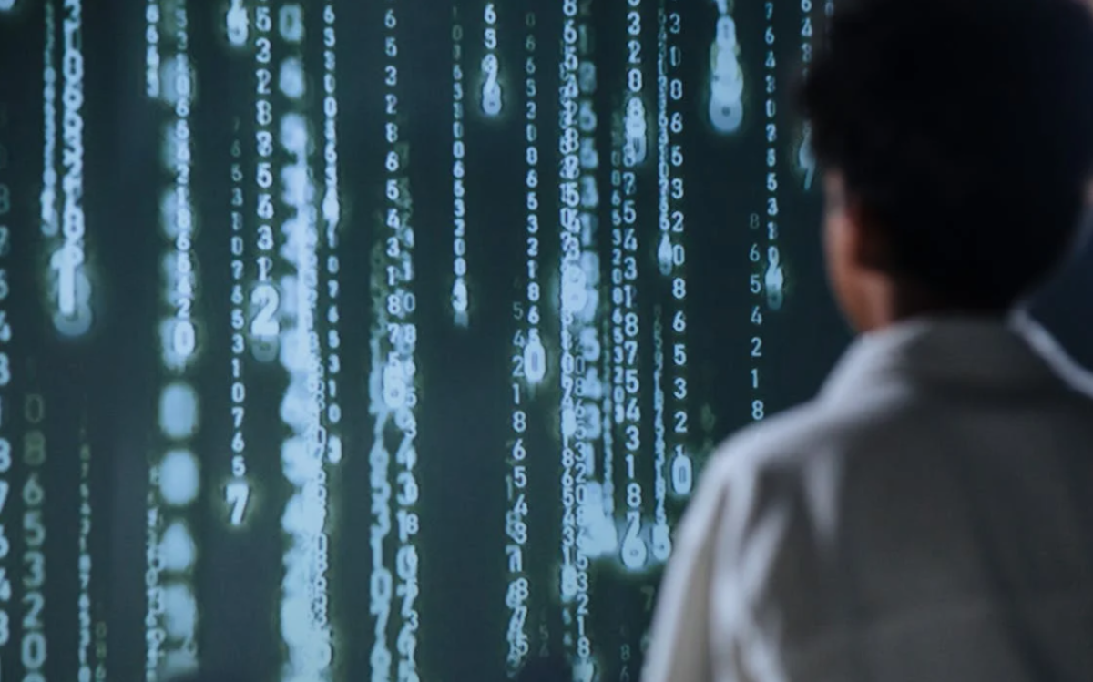 The image depicts a person silhouetted against a backdrop of cascading lines of digital code, suggesting a focus on technology, data, or computer-related tasks.