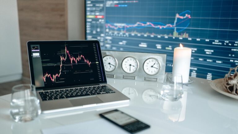 Financial data and market analysis displayed on multiple screens and a laptop, representing strategic decision-making in improving ROI security spend.